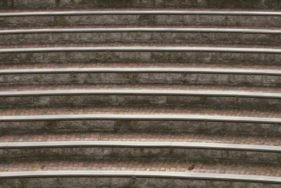 Concentric stone seating steps with moss growing in between, creating a textured and layered appearance. The alternating pattern of stone and brick is evident, with subtle natural wear adding character.