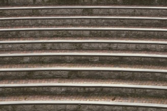 Concentric stone seating steps with moss growing in between, creating a textured and layered appearance. The alternating pattern of stone and brick is evident, with subtle natural wear adding character.