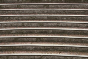 Concentric stone seating steps with moss growing in between, creating a textured and layered appearance. The alternating pattern of stone and brick is evident, with subtle natural wear adding character.
