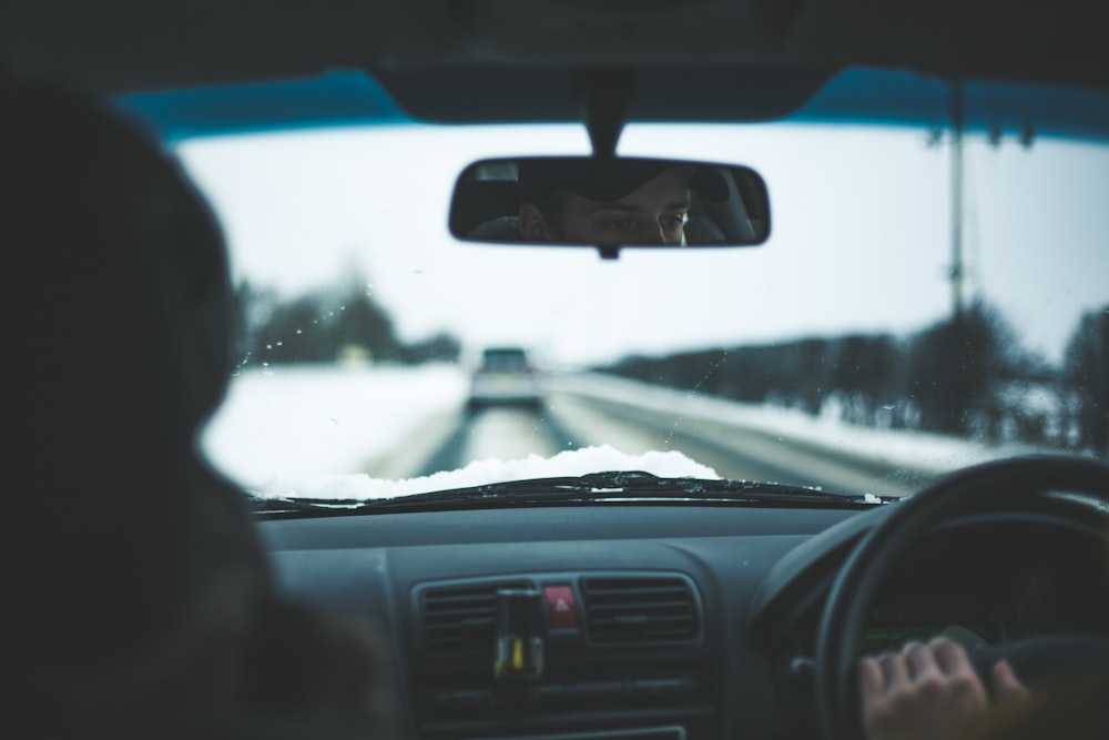 uomo all'interno dell'auto vicino agli alberi durante il giorno