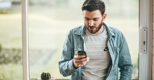 man holding a smartphone near the window