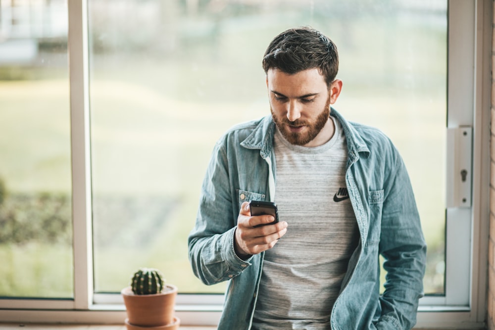 man holding a smartphone near the window