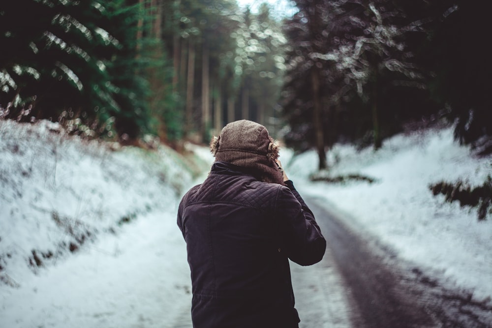 man in brown jacket standing between trees