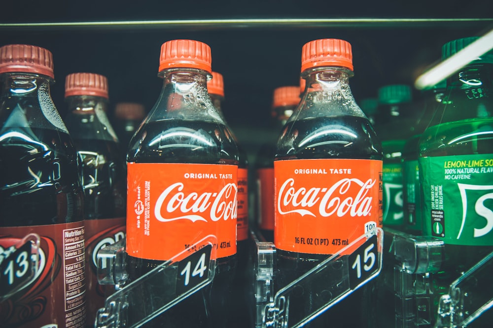 Coca-Cola bottles in between Sprite and another bottle