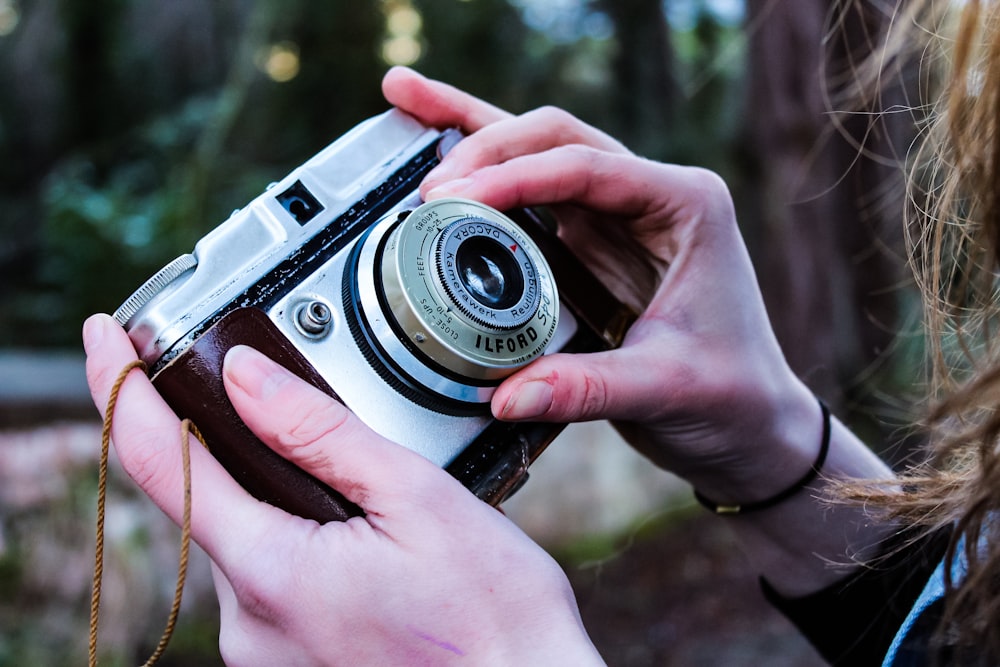 person holding point-and-shoot camera adjusting a lens