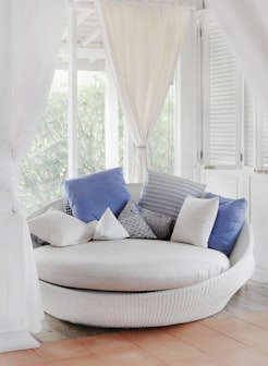 white cuddle chair and throw pillows near window