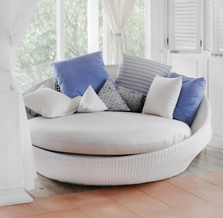 white cuddle chair and throw pillows near window