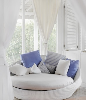 white cuddle chair and throw pillows near window