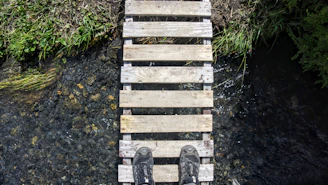 Hikers crossing a wooden bridge over a crystal-clear river in Sweden.
