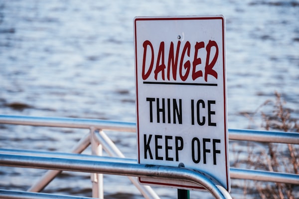 Danger thin ice keep off sign in front of water