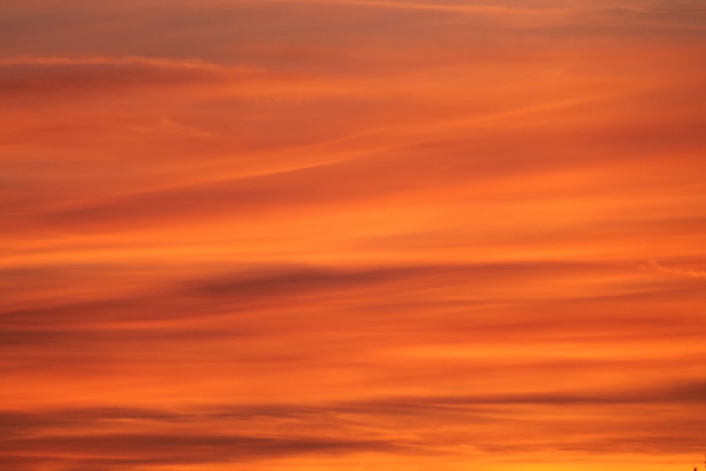 a plane flying in the sky at sunset