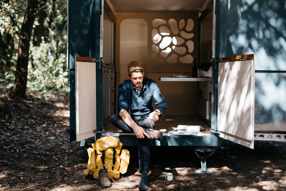 man sitting in the trailer while tieing his shoes