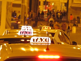 A modern taxi car from Taksi Al-Salam parked in a city street at night with bright lights.