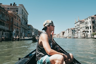 man riding boat surrounded with buildings during daytime