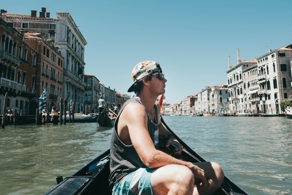 man riding boat surrounded with buildings during daytime