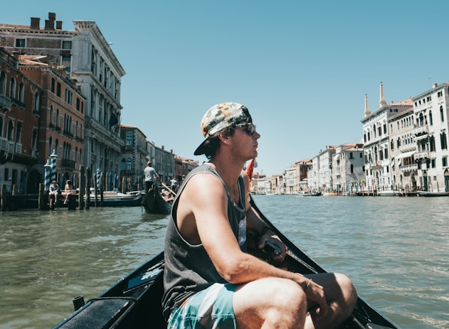 man riding boat surrounded with buildings during daytime