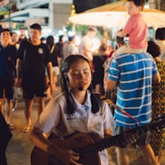 selective focus photo of girl playing guitar and singing