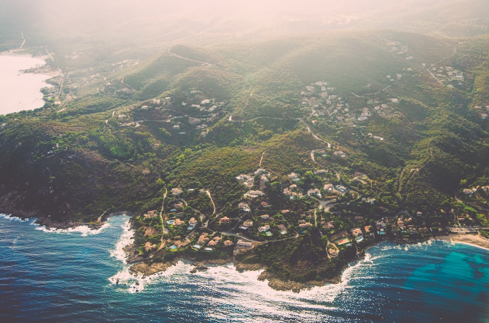 bird's eye view photo of green mountain peak near body of water