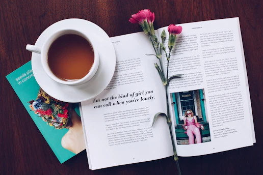 A cozy reading nook with a copy of '10 ways to become your best version' resting on a wooden table beside a steaming cup of tea.