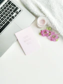 A cozy flat lay of personalized items including a thermos, notebook, and delicate floral details in neutral tones.