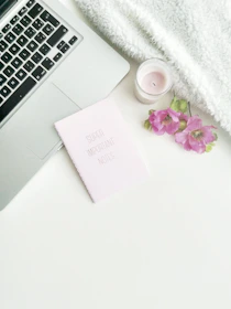 An elegant flat lay of a tablet, headphones, and a journal resting on a cream white blanket with star accents.