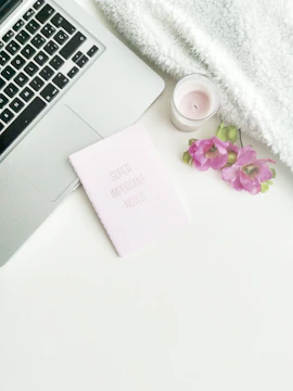 An elegant flat lay of a content strategy plan with notes and a laptop illuminated by soft pink lighting.