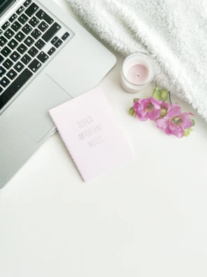 A cozy flat lay of personalized items including a thermos, notebook, and delicate floral details in neutral tones.
