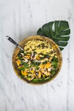 A vibrant bowl filled with fresh greens, grains, and colorful veggies on a rustic wooden table.