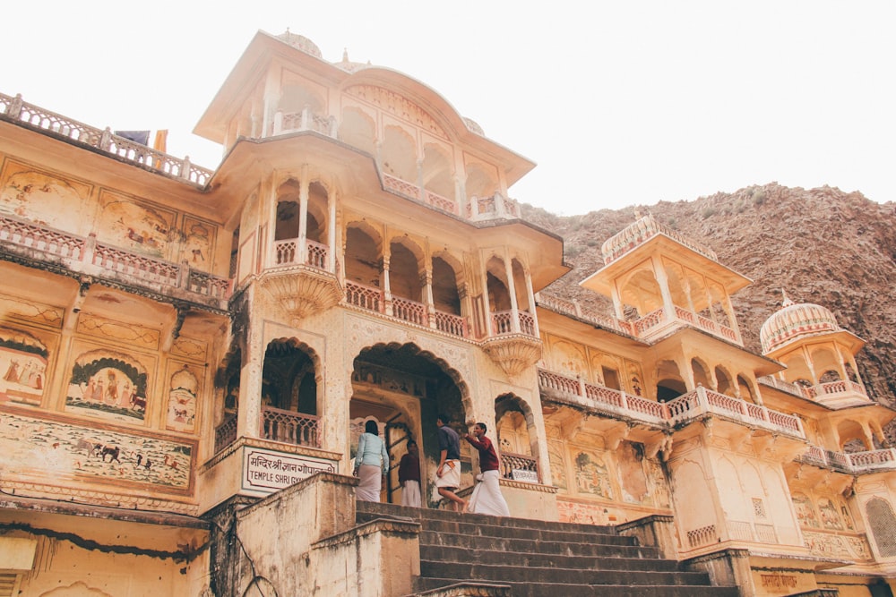 people entering the entrance of beige temple at daytime