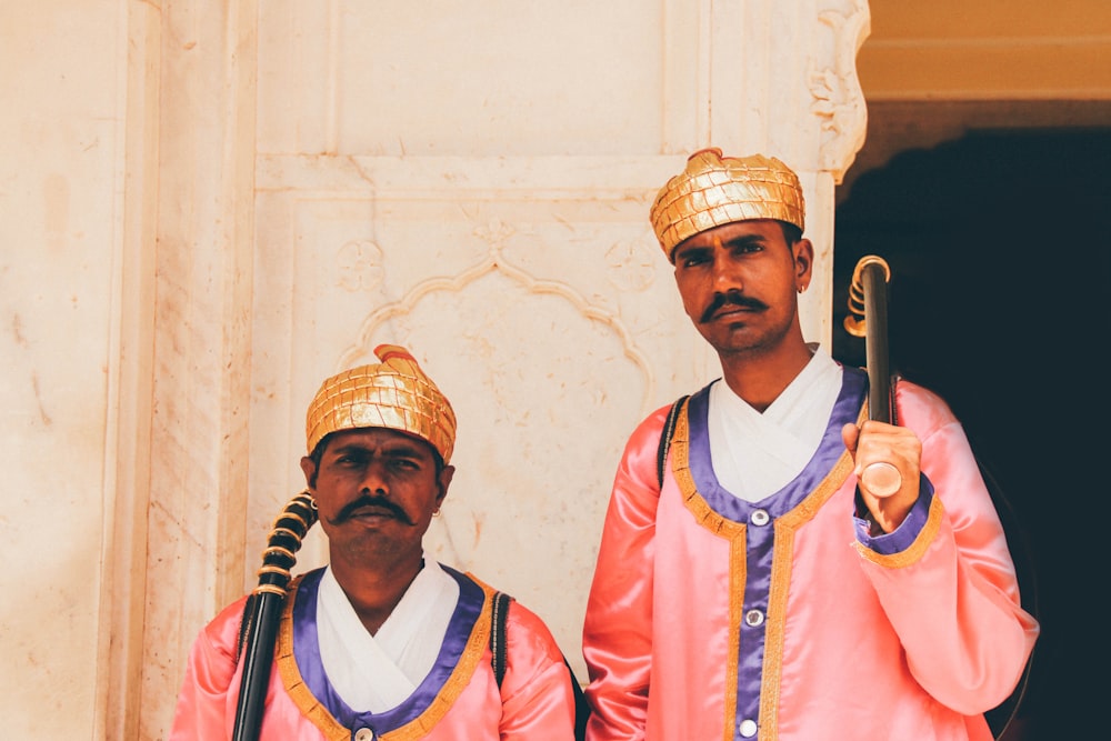 two men holding black wooden stick