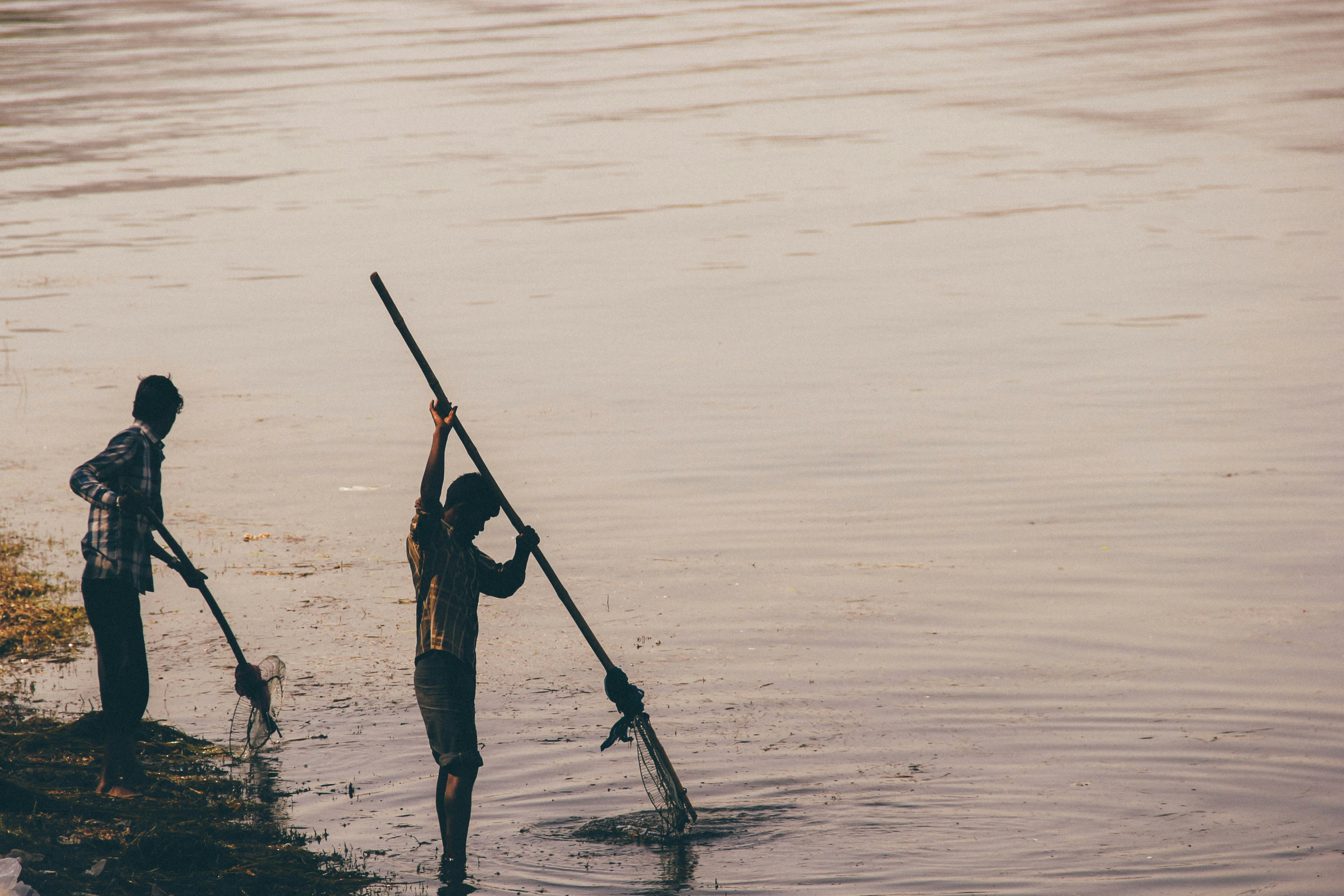 Dos hombres pescando en un cuerpo de agua durante el día