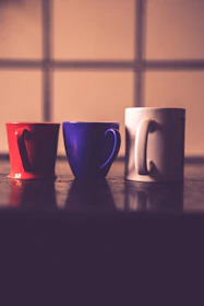 A set of three colorful mugs lined up side by side.