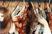 person holding assorted clothes in wooden hanger