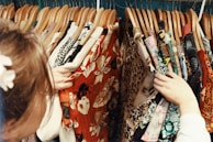 Hands selecting colorful garments from a hanging rack in a boutique.