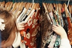 A close-up of hands sorting through sustainable fabrics and vintage clothing.