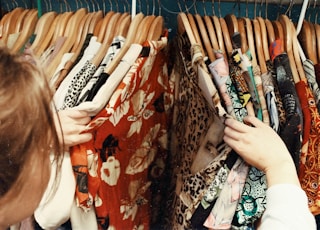 person holding assorted clothes in wooden hanger