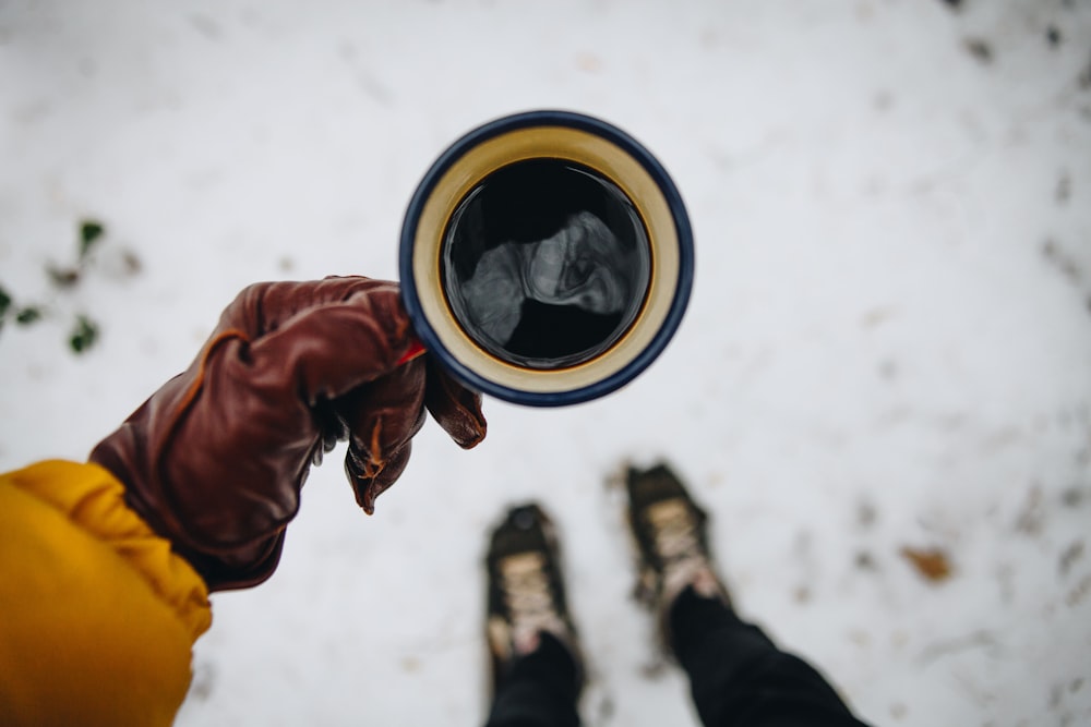 Persona che tiene la tazza di caffè con caffè nero