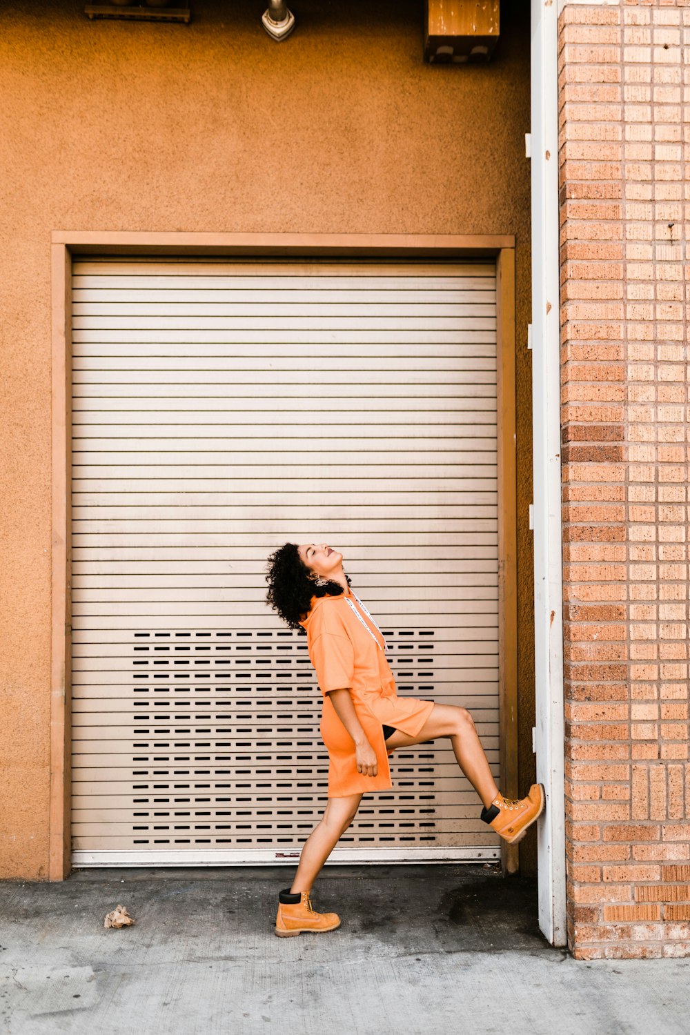 woman stepping her right foot on wall near roller shutter