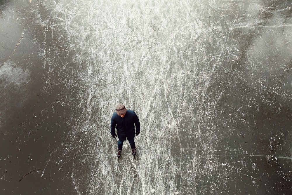 낮에 얼어붙은 물 위에 서 있는 검은색 재킷을 입은 남자