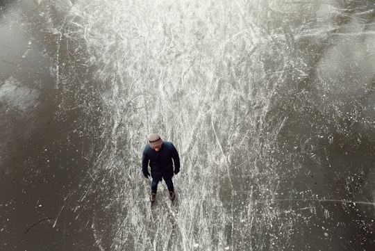 man wearing black jacket standing on frozen body of water during daytime in Utrecht Netherlands