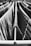 Clothes hang on a drying rack with thin metal rods, featuring a mixture of light and dark fabrics. The perspective is up close, emphasizing the texture and pattern of the clothing. The image is in black and white, creating a classic and timeless feel.