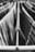 Clothes hang on a drying rack with thin metal rods, featuring a mixture of light and dark fabrics. The perspective is up close, emphasizing the texture and pattern of the clothing. The image is in black and white, creating a classic and timeless feel.