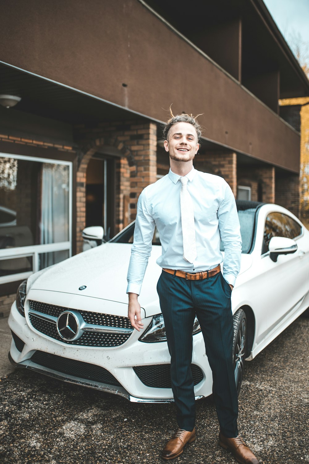 hombre de pie delante en un cupé blanco de Mercedes-Benz