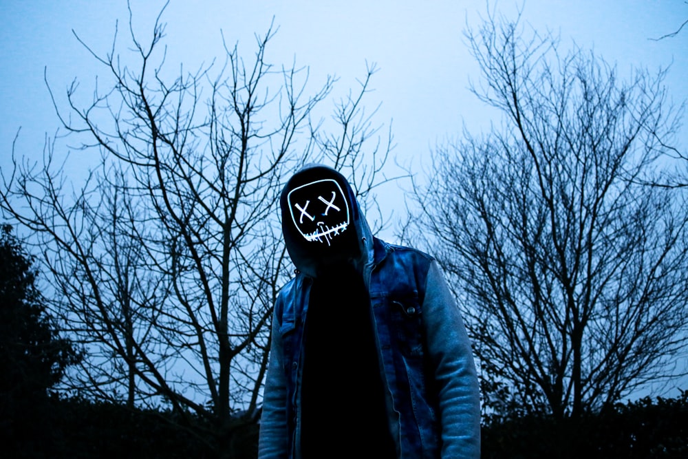 a person wearing a mask standing in front of trees