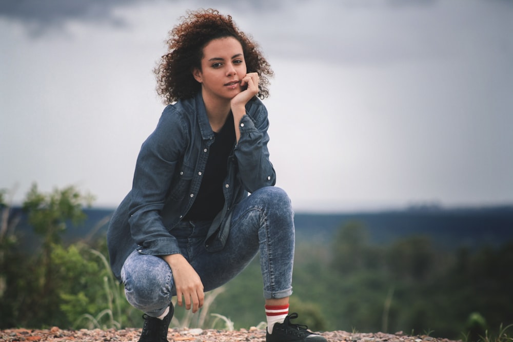 woman crouching on sand hands on chin