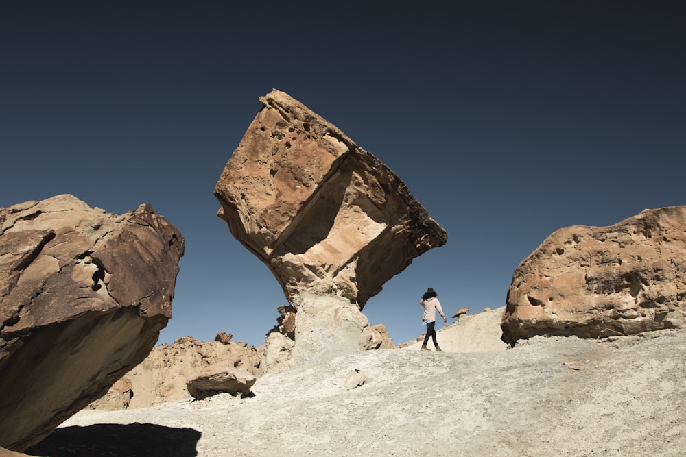 woman standing under brown rock formation at daytime