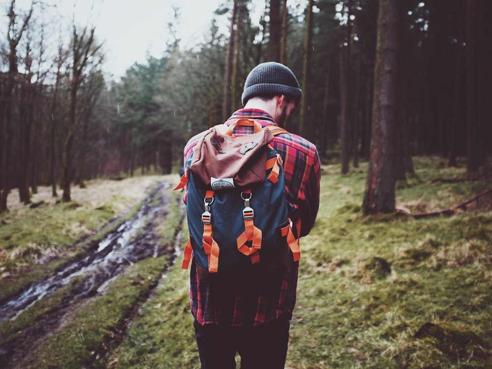 man carrying backpack standing surrounded by tree