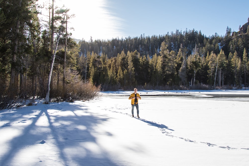 man walking in snow plain near forest