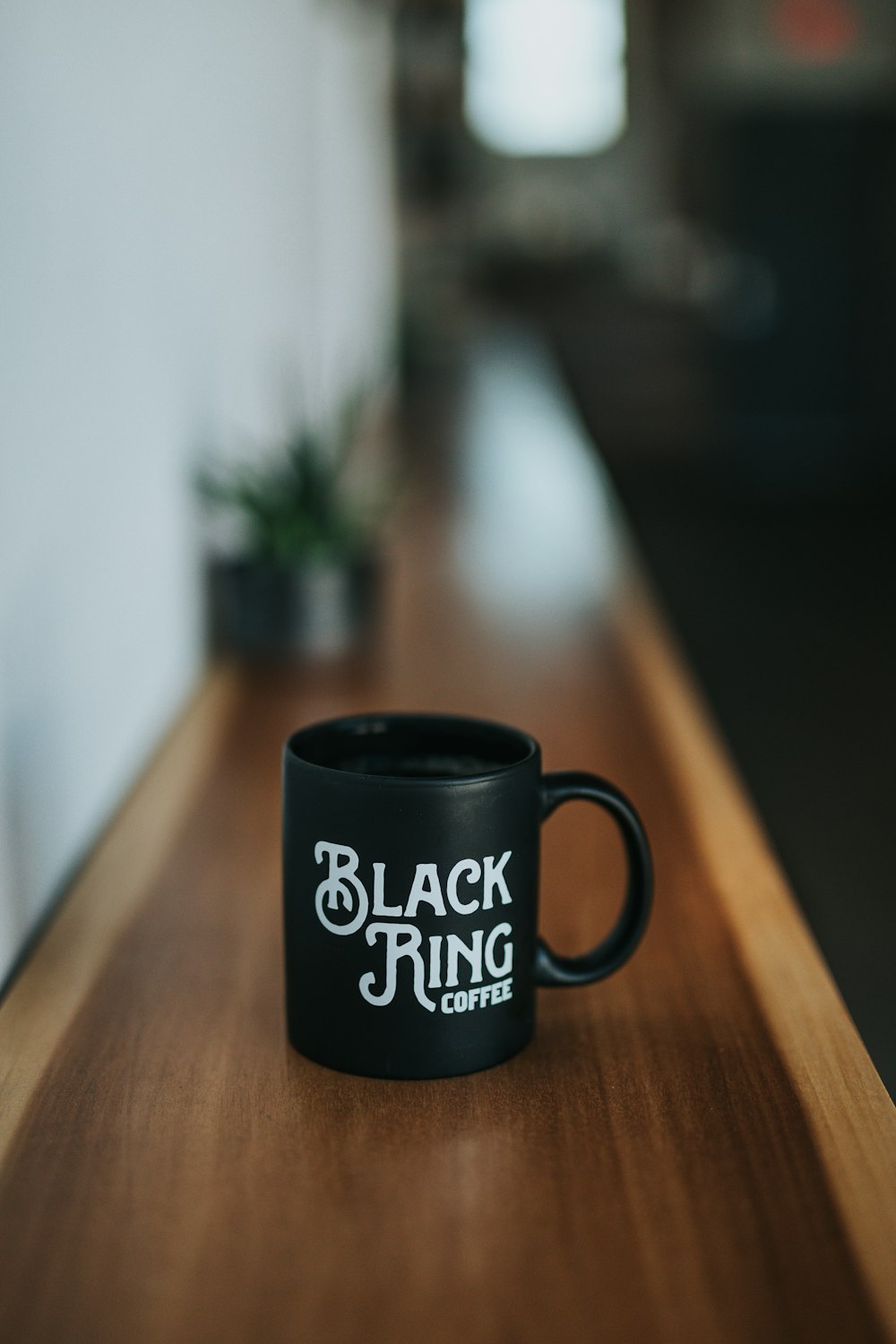 茶色の木の表面に黒のブラックリングコーヒーセラミックコーヒーマグカップ