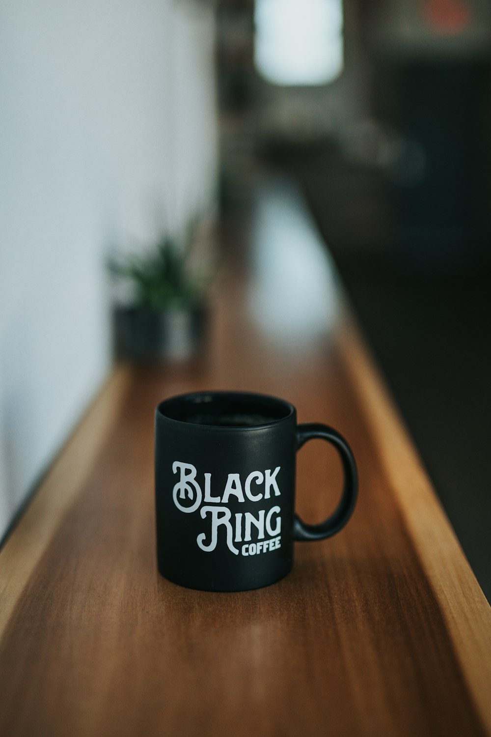 Taza de café de cerámica Black Ring Coffee negra sobre superficie de madera marrón